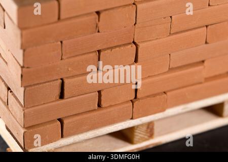 Stack of red clay bricks neatly arranged on a wooden pallet, ready for construction Stock Photo