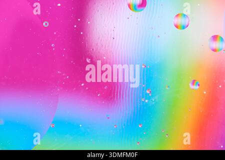 Artistic abstract liquid art with oil drops on pink, blue and green blurred background Stock Photo