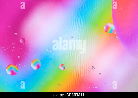 Bright abstract background featuring rainbow colors and floating liquid spheres in macro scale Stock Photo