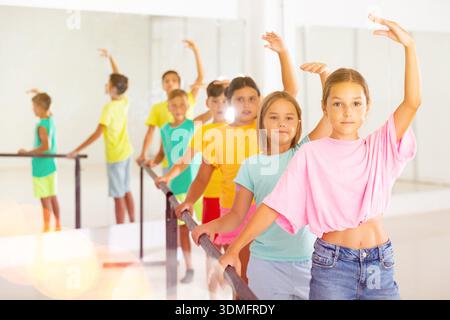Diligent tween girl practicing classic dance moves near ballet barre Stock Photo