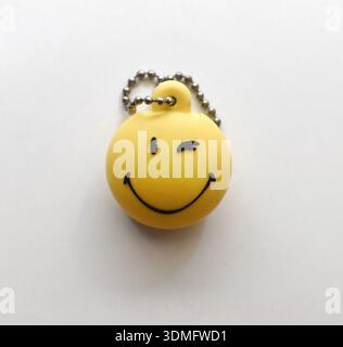 High-quality photograph of a happy face keychain placed on a clean white table. Perfect for product photography, lifestyle blogs, social media, e-comm Stock Photo