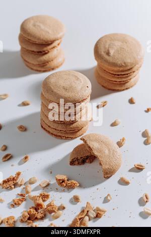 Stacked peanut macarons with bitten cookie and crumbs on white background Stock Photo