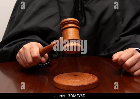 Wooden judge gavel raised above sounding block on court table Stock Photo