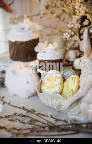 Easter still life with white bunny, decorated cakes and egg cookies Stock Photo