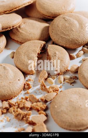 Broken peanut macarons with crumbs and nuts on white background, close up Stock Photo