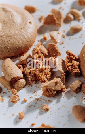 Peanut macaron crumbs and broken cookie pieces on white background, hard light Stock Photo