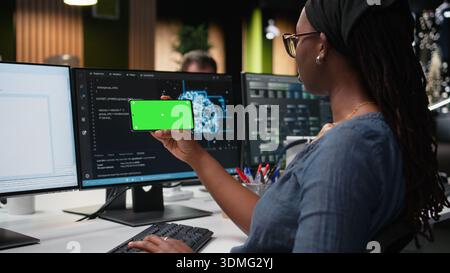 Isolated screen smartphone used by admin in office working to fix bugs in artificial intelligence system. Employee in tech startup using chroma key mockup mobile phone to watch videos Stock Photo