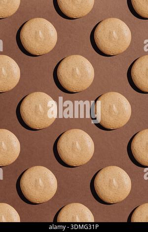 Seamless pattern of beige macarons with hard shadows on brown background Stock Photo