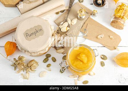 Health food concept in vintage apothecary style. Homemade pumpkin puree and hummus in glass jars on a white wooden table. Rustic autumnal still life w Stock Photo