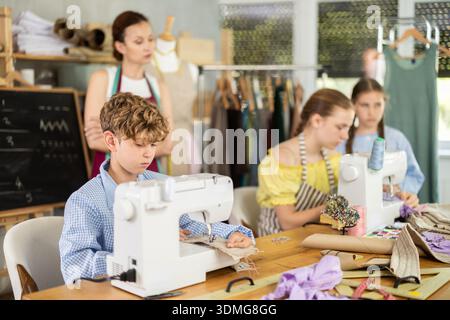 Engaged schoolboy stitching fabric on machine in sewing class Stock Photo