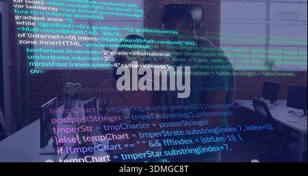 Reviewing source code, female in pink blouse and male colleague at office with monitors and headset Stock Photo