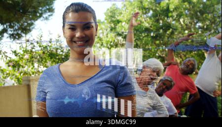 Leading female instructor wearing blue T-shirt guiding seniors on patio with digital overlays Stock Photo