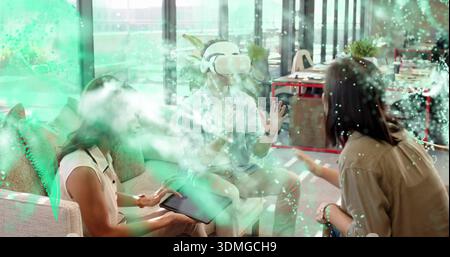 Showing team using VR headset and tablet in office lounge, displaying augmented interface Stock Photo