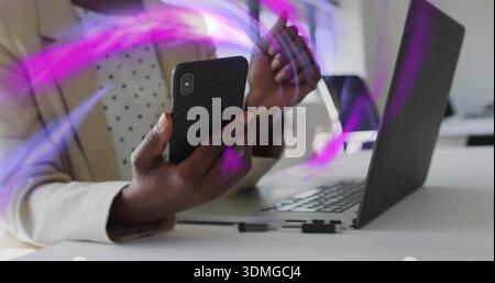 Using black phone, woman in cream blazer, dotted top gesturing at office with laptop, purple trails Stock Photo