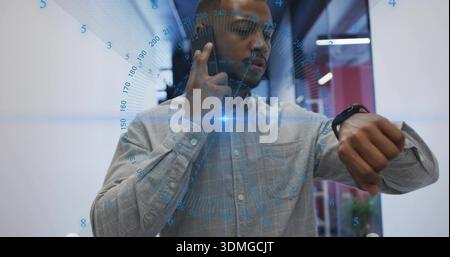 Holding phone to ear, worker wearing gray checked shirt checking watch in office corridor with HUD Stock Photo
