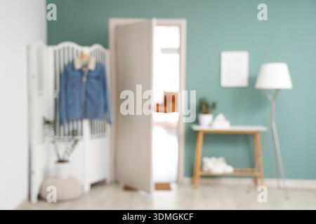 Blurred view of modern hallway  with bench, folding screen and pouf near mint wall Stock Photo