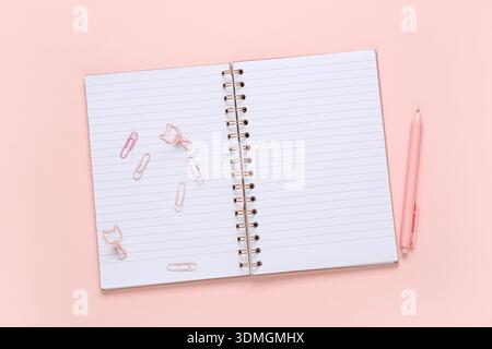Blank open notebook, paper clips and pen on pink background Stock Photo