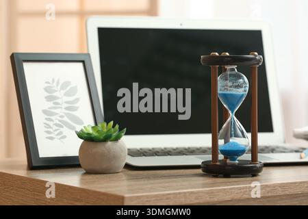 Hourglass with laptop and succulent on table in office Stock Photo