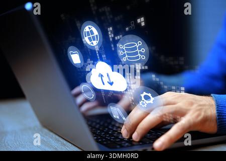 Working on a laptop with cloud storage icons at night in a modern setting with technology Stock Photo