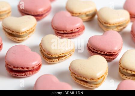 A variety of heart shaped macarons in different colors are placed on a white surface. Stock Photo