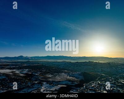 A beautiful blue sky with a sun setting in the distance. The sky is clear and the sun is setting behind the mountains Stock Photo