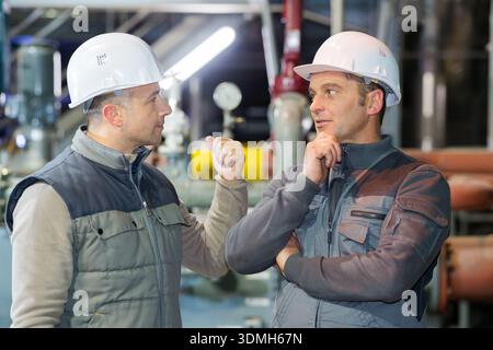 two factory workers talking in production plant Stock Photo