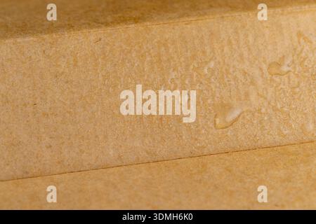 wet hard yellow cardboard for packaging goods and products, part of the corrugated cardboard packaging is covered with water droplets Stock Photo