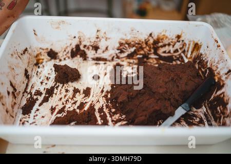 Close-up of rich dark chocolate dough being prepared in a white plastic tray with a knife Stock Photo