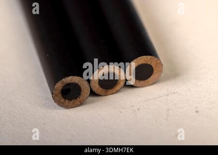 a row of black wooden pencils folded on cheap loose paper, pencils with graphite lead for drawing or other work Stock Photo