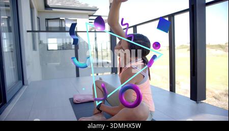 Practicing woman stretching on home balcony in pink tank top, shorts with yoga mat, neon graphics Stock Photo