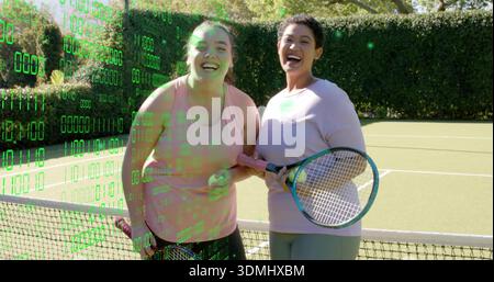 Standing two women laughing holding racket, ball at tennis court near net in pink binary overlay Stock Photo