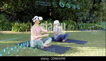 Family pair stretching on yoga mats in garden wearing workout tops using VR and AR overlays Stock Photo