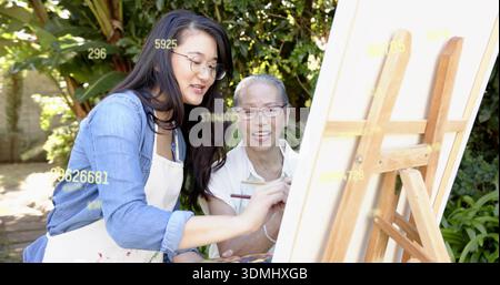 Painting denim instructor in apron guiding student in blouse by wooden easel, canvas, copy space Stock Photo