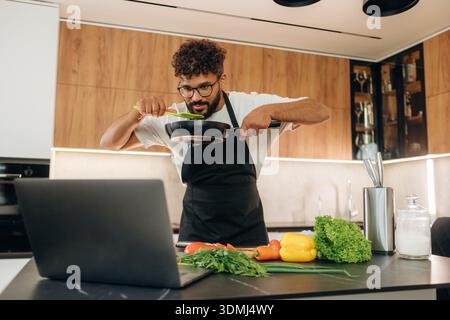 Fresh vegetables, making salad. Handsome man is preparing food on the kitchen. Stock Photo
