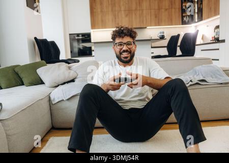 Enjoying playing video games, with controller. Man is in the modern domestic room at home. Stock Photo