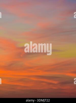 Clear evening sky displaying a beautiful contrast between blue atmosphere and bright orange clouds with jet contrails. Stock Photo