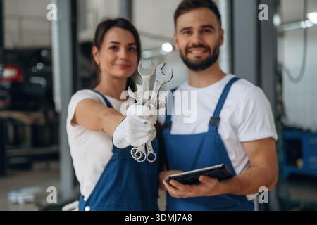 Showing the tools. Auto repair shop employees are working together. Man and woman. Stock Photo