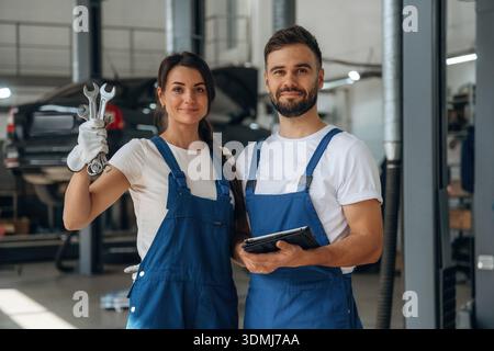 Showing the tools. Auto repair shop employees are working together. Man and woman. Stock Photo