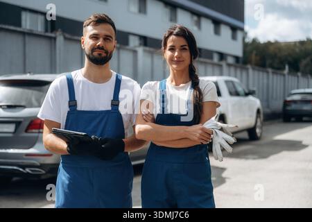 Cheerful male and female mechanics are standing outdoors together. Stock Photo