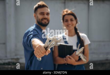Cheerful male and female mechanics are standing outdoors together. Stock Photo