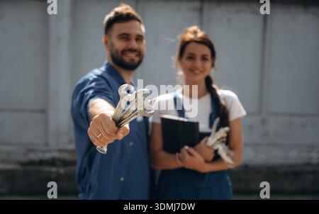 Cheerful male and female mechanics are standing outdoors together. Stock Photo