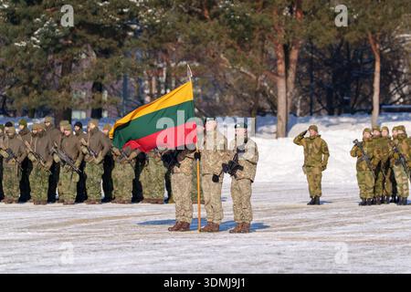 Lithuanian soldiers in camouflage uniforms holding the national flag in a snowy field. Stock Photo