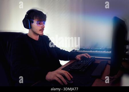 Young man using computer with led cyber glasses and headphones Stock Photo