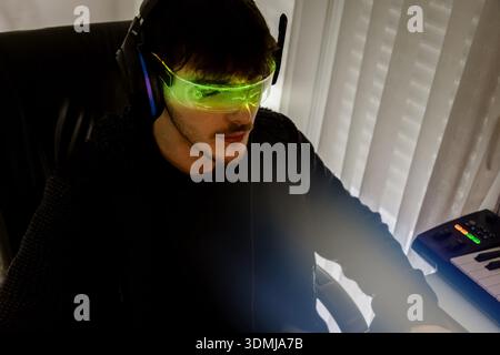 Young man using computer with led cyber glasses and headphones Stock Photo