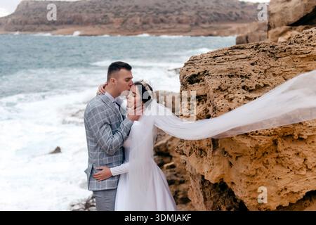 Happy just married young couple on a rock by the sea Stock Photo