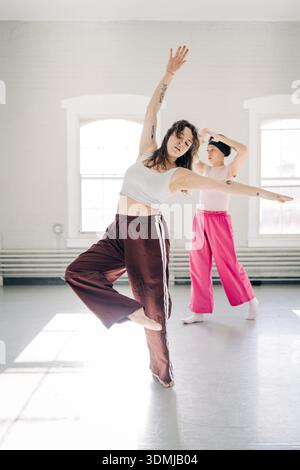 Dancers practicing modern dance in studio with sunlight Stock Photo