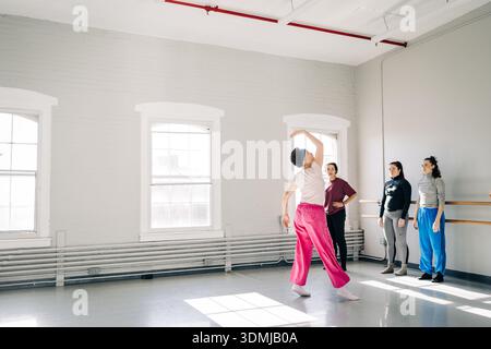 Dancer practicing movement with group in studio Stock Photo