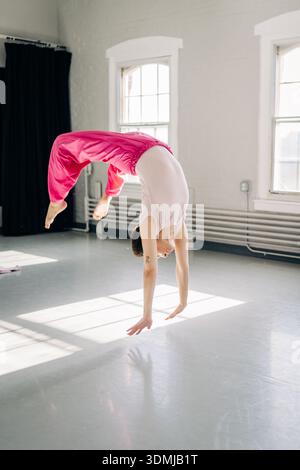 Female dancer performing a handspring in bright studio Stock Photo