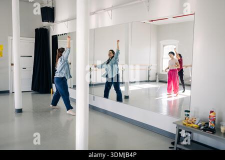 Female dancers rehearsing movement in spacious dance studio Stock Photo