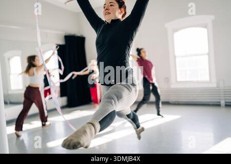 Gymnast performing rhythmic ribbon routine in bright studio Stock Photo